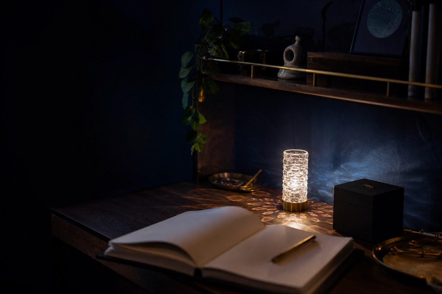 Dark desk corner with crystal mood light, notebook, shelf objects, and gift box
